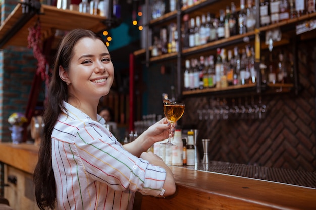 Giovane donna affascinante che gode di un drink al bar