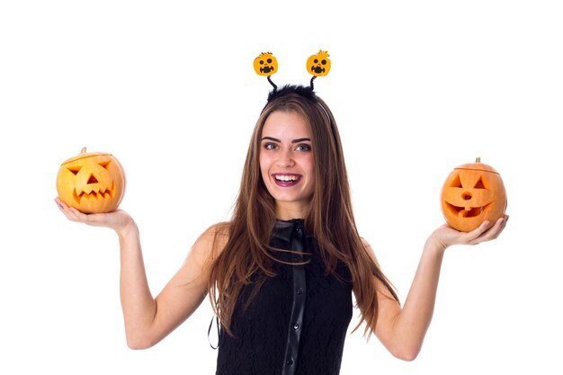 Giovane donna affascinante in abito nero che tiene una zucca tra le mani su sfondo bianco in studio