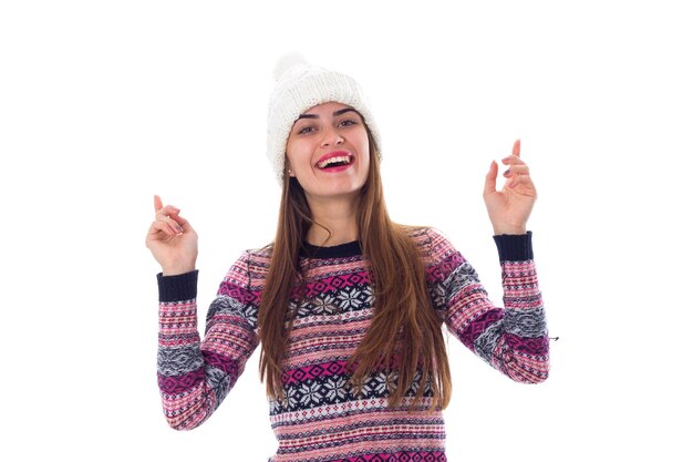 Giovane donna affascinante in maglione viola e cappello bianco su sfondo bianco in studio