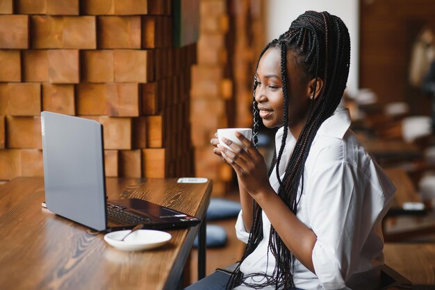 Giovane donna africana al caffè che beve caffè