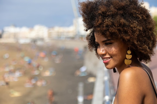 Giovane donna africana che guarda la spiaggia dal lungomare