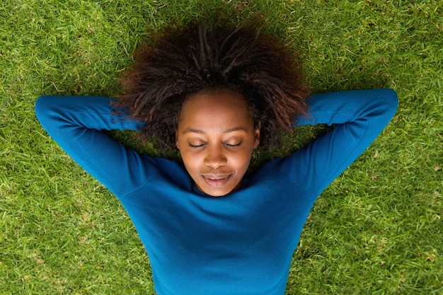 Giovane donna africana che si trova sul sonno dell&#39;erba