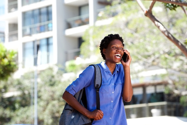 Giovane donna africana felice che ride con il telefono cellulare all&#39;aperto