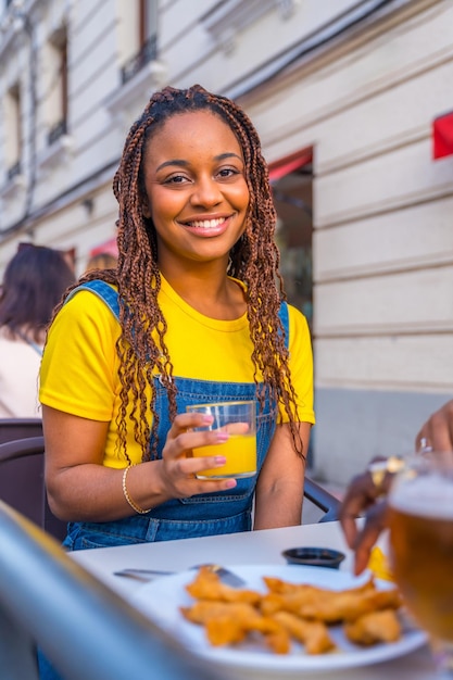 Giovane donna africana seduta su una terrazza di un ristorante