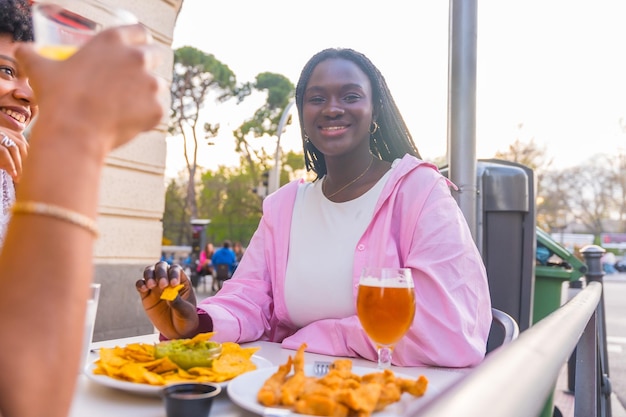 Giovane donna africana sorridente che mangia nachos con gli amici