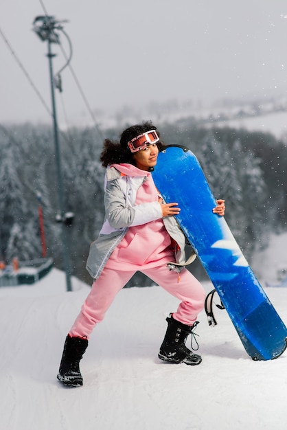 Giovane donna africana su sci, sport invernali snowboard concetto indossando occhiali protettivi, sani