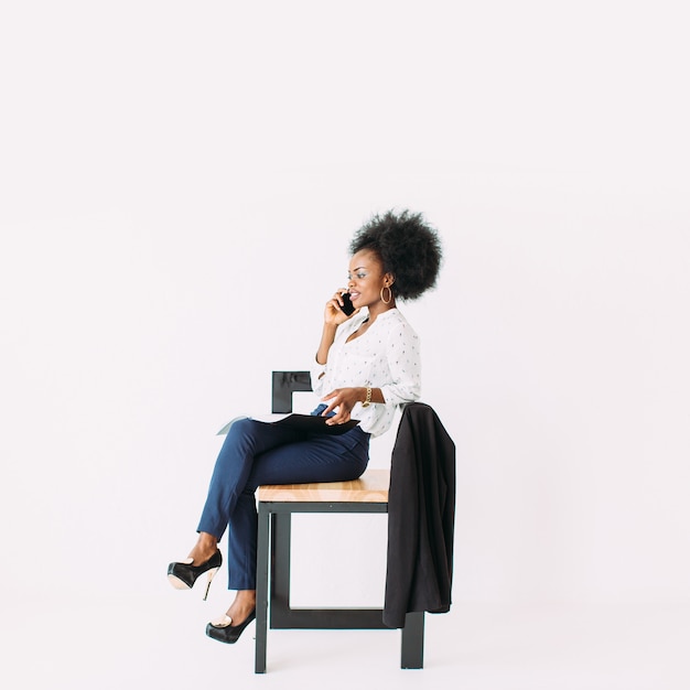 Giovane donna afro-americana di affari che parla al telefono mentre era seduto sulla sedia