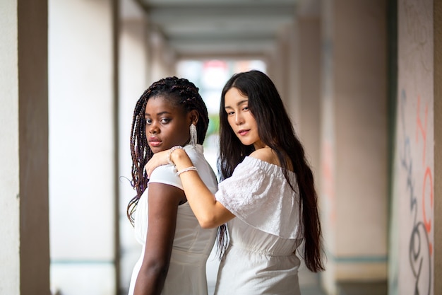 Giovane donna afro-americana e caucasica donna in abiti bianchi