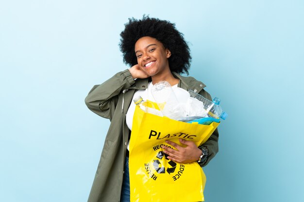 Giovane donna afro-americana in possesso di un sacchetto di riciclo isolato sulla risata colorata