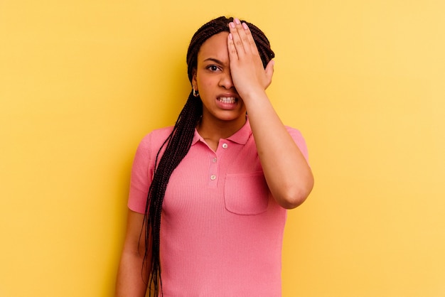 Giovane donna afro-americana isolata su sfondo giallo dimenticando qualcosa, schiaffi sulla fronte con il palmo e chiudendo gli occhi.