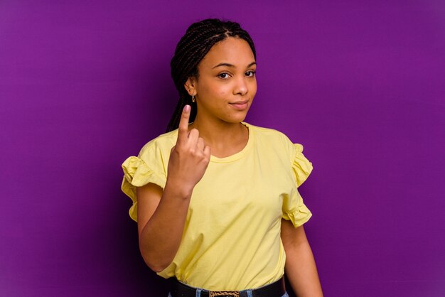 Giovane donna afro-americana isolata sul muro giallo che punta il dito contro di te come se invitando ad avvicinarsi