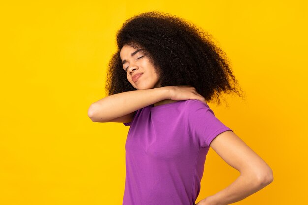 Giovane donna afro-americana sul muro isolato che soffrono di dolore alla spalla per aver fatto uno sforzo