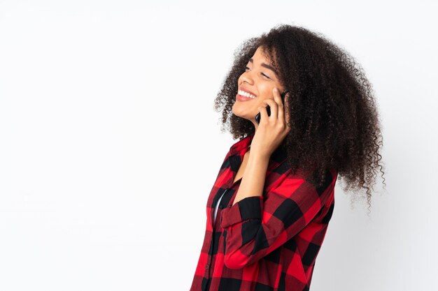 Giovane donna afro-americana sul muro mantenendo una conversazione con il telefono cellulare con qualcuno