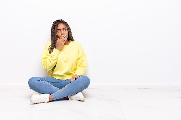 Giovane donna afro che sbadiglia pigramente al mattino presto, svegliarsi e sembrare assonnato, stanco e annoiato