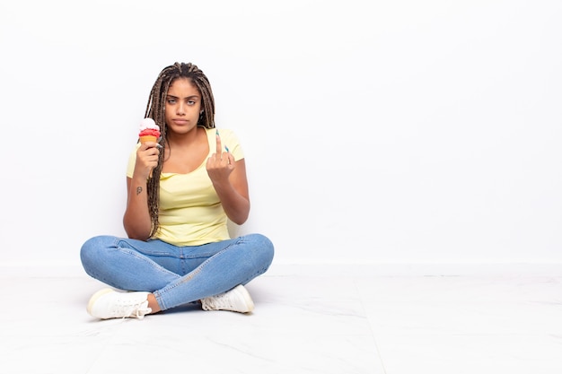 Giovane donna afro che si sente arrabbiata, infastidita, ribelle e aggressiva, lancia il dito medio, reagisce