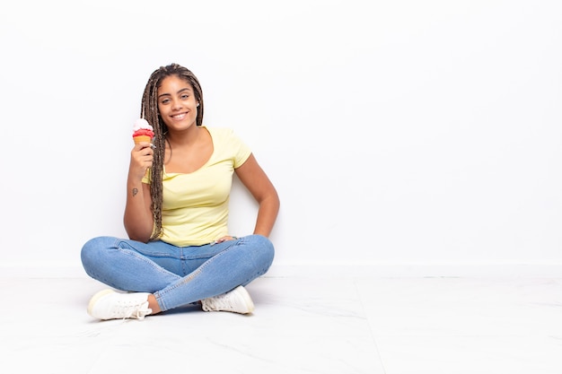 Giovane donna afro che sorride felicemente con una mano sull'anca e sicura