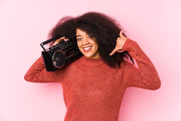 Giovane donna afro che tiene un cassete isolato che mostra un gesto di chiamata di telefono cellulare con le dita.