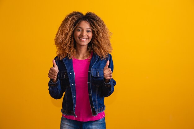 Giovane donna afro con il pollice in su facendo segno ok e positivo.