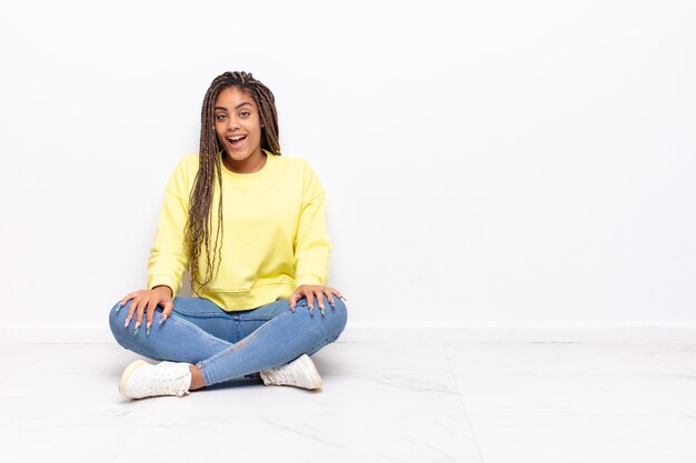 giovane donna afro con un sorriso grande, amichevole e spensierato, dall'aspetto positivo, rilassato e felice, agghiacciante