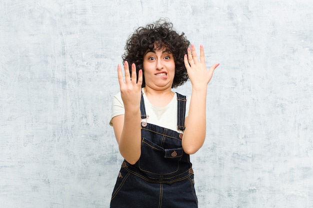 Giovane donna afro graziosa che sorride e che sembra amichevole, mostrando numero nove o nono con la mano in avanti, conto alla rovescia