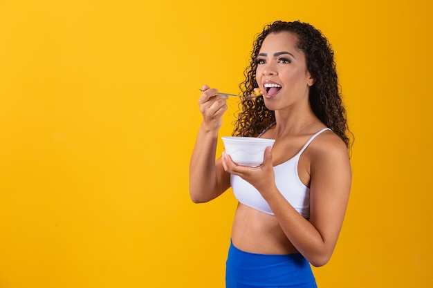 Giovane donna afro in buona salute che mangia macedonia.