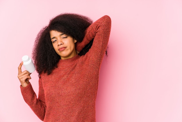 Giovane donna afro in possesso di un toccando vitamine retro della testa, pensando e fare una scelta.