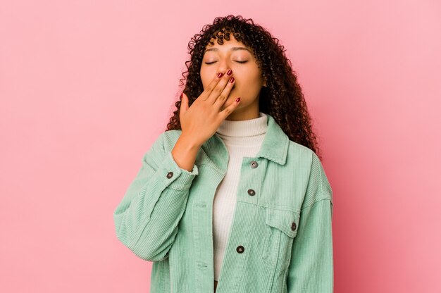 Giovane donna afro isolata che sbadiglia mostrando un gesto stanco che copre la bocca con la mano