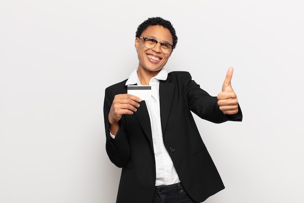 Giovane donna afro nera che si sente orgogliosa, spensierata, sicura e felice, sorridendo positivamente con i pollici in su