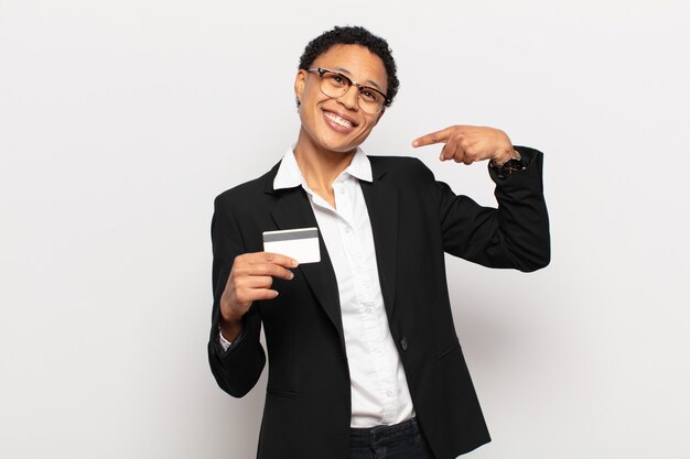 giovane donna afro nera che sorride fiduciosamente indicando il proprio ampio sorriso, atteggiamento positivo, rilassato, soddisfatto