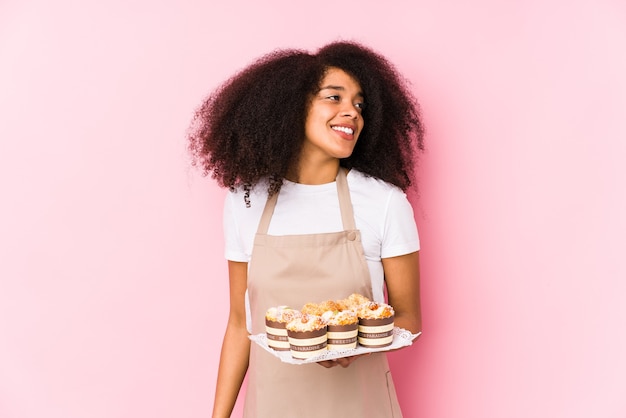 Giovane donna afro pasticciera che tiene un cupcakes isolato