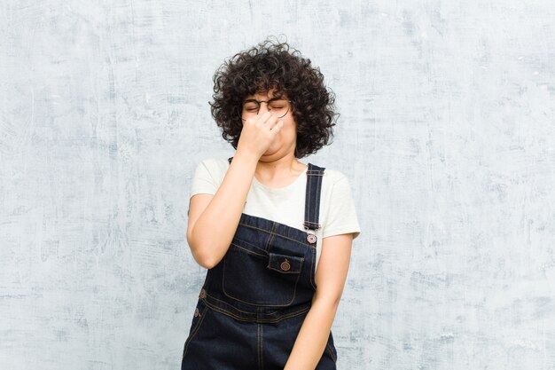 Giovane donna afro sentirsi disgustata, trattenendo il naso per evitare di annusare un cattivo odore sgradevole