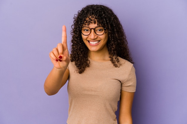 Giovane donna afroamericana afro isolata che mostra il numero uno con il dito.