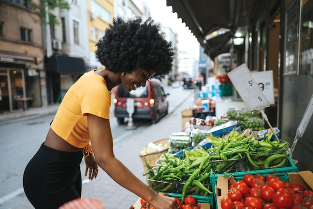 Giovane donna afroamericana che acquista in un mercato di strada locale