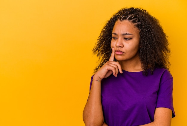 Giovane donna afroamericana che guarda lateralmente con espressione dubbiosa e scettica.