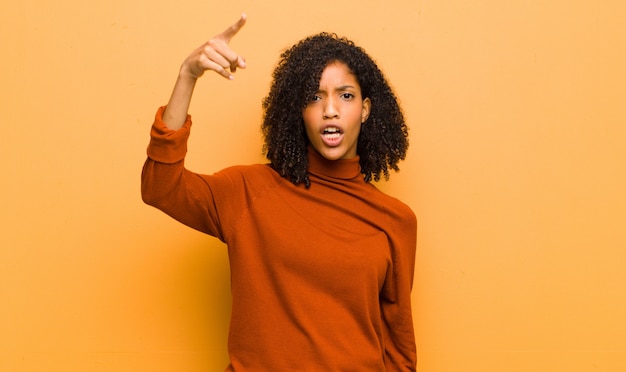 giovane donna afroamericana che posa mentre indicando nervosamente con il dito