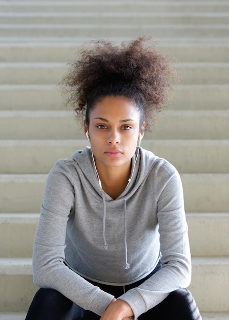 Giovane donna afroamericana che si siede sui punti con le cuffie