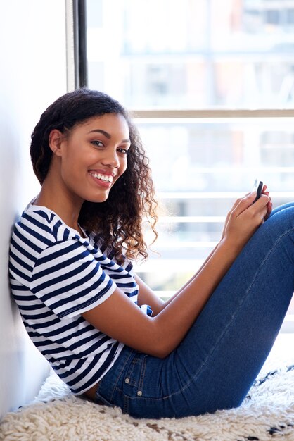 Giovane donna afroamericana che sorride con il cellulare