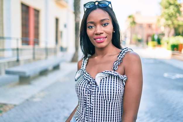 Giovane donna afroamericana che sorride felice camminando per la strada della città