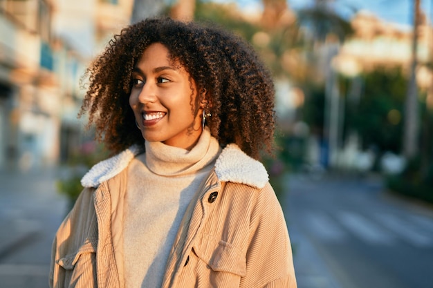 Giovane donna afroamericana che sorride felice in piedi in città