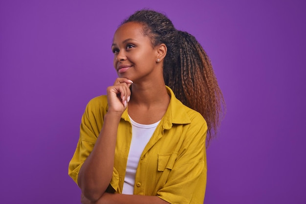 Giovane donna afroamericana che tocca il mento sognando risultati di carriera