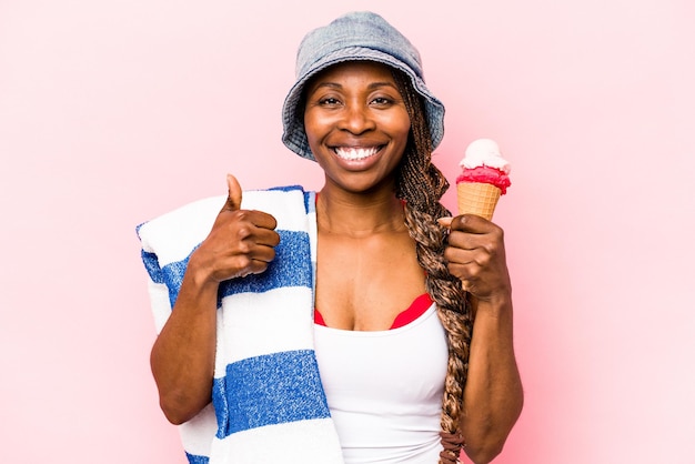 Giovane donna afroamericana che va in spiaggia tenendo un gelato isolato su sfondo rosa