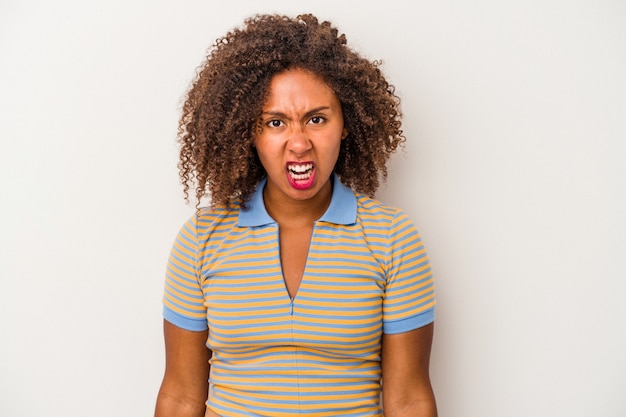 Giovane donna afroamericana con capelli ricci isolata su fondo bianco che grida molto arrabbiato, concetto di rabbia, frustrato.