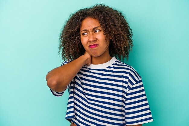 Giovane donna afroamericana con capelli ricci isolati su fondo blu che tocca la parte posteriore della testa, pensando e facendo una scelta.