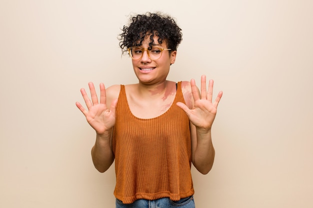 Giovane donna afroamericana con il segno di nascita della pelle che rifiuta qualcuno che mostra un gesto di disgusto.