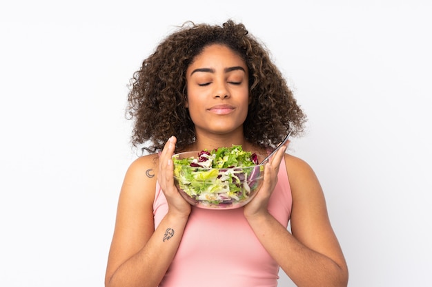 Giovane donna afroamericana con insalata sulla parete bianca