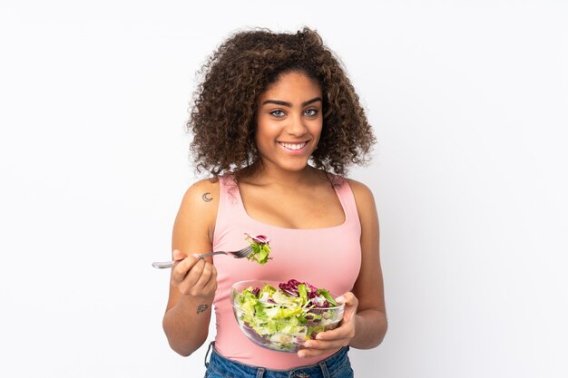 Giovane donna afroamericana con insalata sulla parete bianca