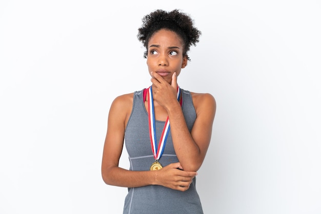 Giovane donna afroamericana con medaglie isolate su sfondo bianco con dubbi e con espressione facciale confusa