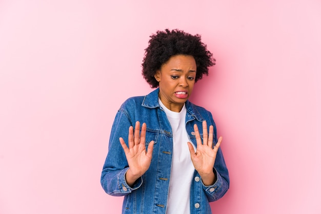 Giovane donna afroamericana contro un backgroound rosa isolato rifiutando qualcuno che mostra un gesto di disgusto.