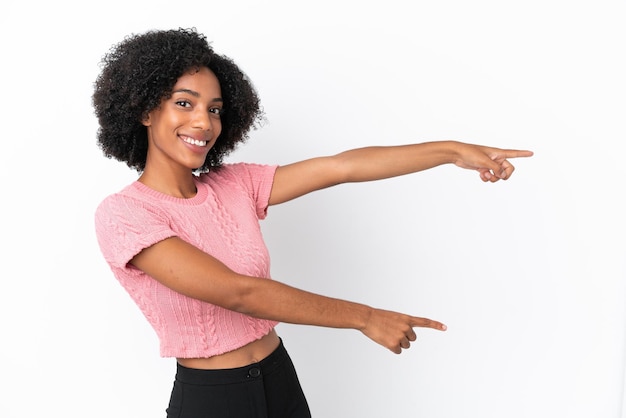 Giovane donna afroamericana isolata su sfondo bianco che punta il dito sul lato e presenta un prodotto