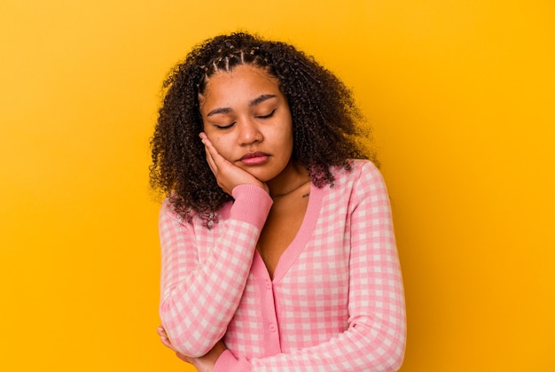 Giovane donna afroamericana isolata su sfondo giallo che è annoiata, affaticata e ha bisogno di una giornata di relax.